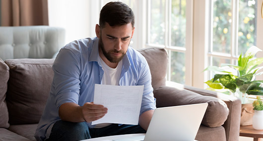 Man reviewing computer and papers. Comparing cd rates