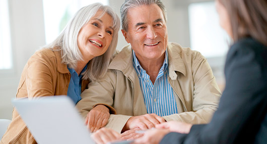 A man and woman sit at a table with a laptop, comparing retirement savings plans like 401(k)s and IRAs for Texas residents.