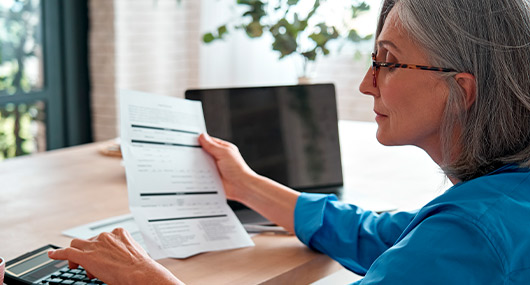 A woman reviews a document on her laptop, focusing on savings accounts and CDs.
