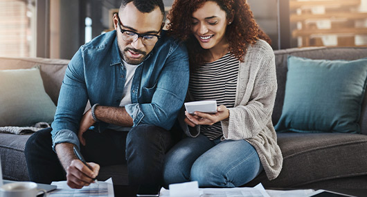 Man and woman using a smartphone to manage their finances, focusing on savings accounts and CDs.