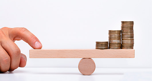 A hand holds a stack of coins on a wooden balance, representing financial choices related to Southern home colors.