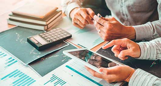 Two individuals collaborate on a tablet and calculator, focusing on end-of-year tax strategies for Texas small businesses.