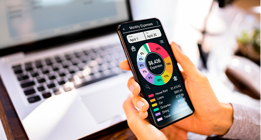 A hand grips a smartphone showing a color wheel, representing financial resolutions for a successful New Year in Texas.